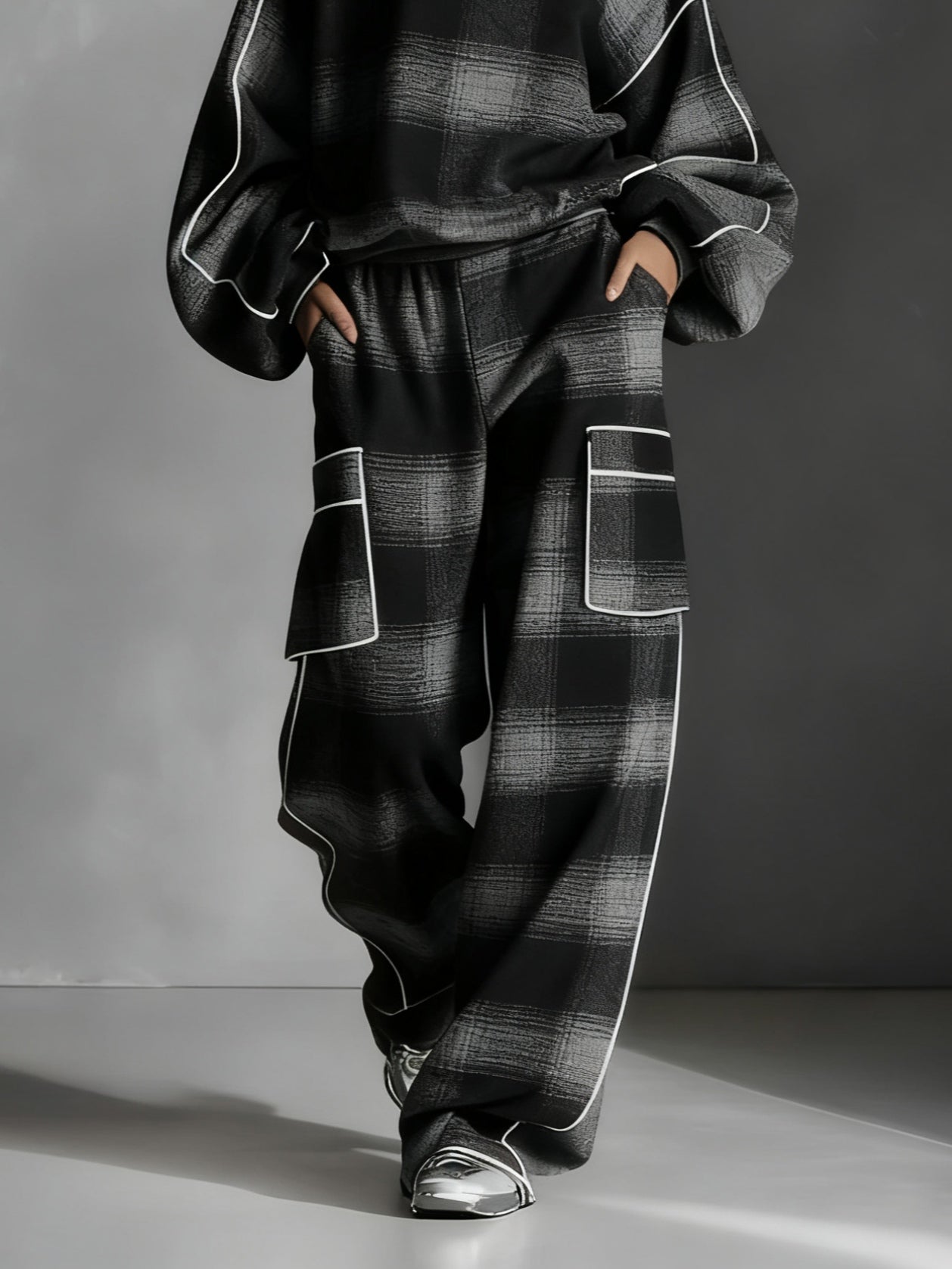 Conjunto de dos piezas compuesto por sudadera con bloques de color a cuadros negros y grises y pantalones informales.