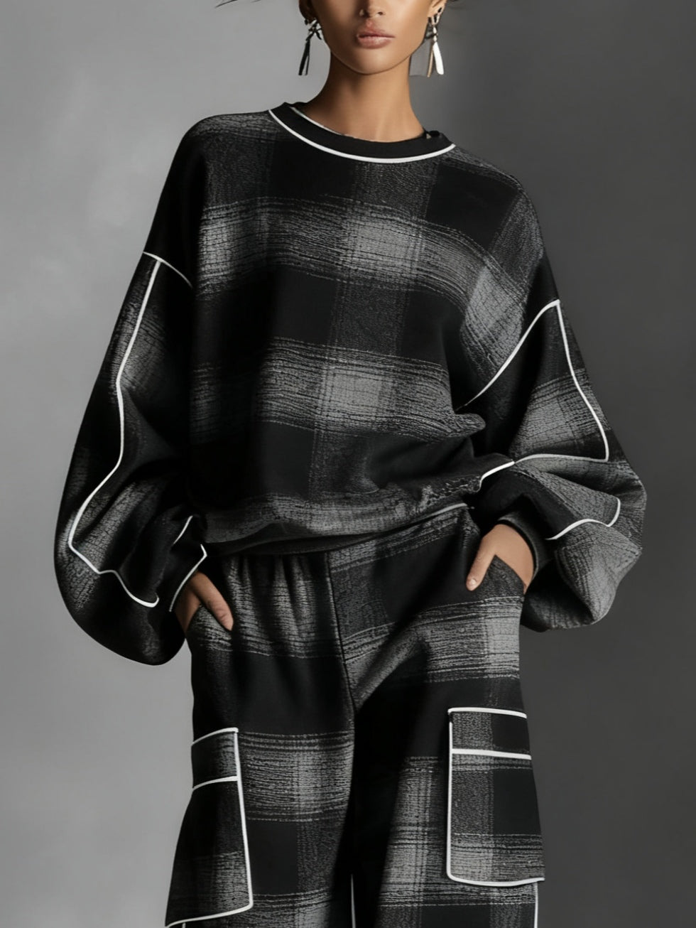 Conjunto de dos piezas compuesto por sudadera con bloques de color a cuadros negros y grises y pantalones informales.